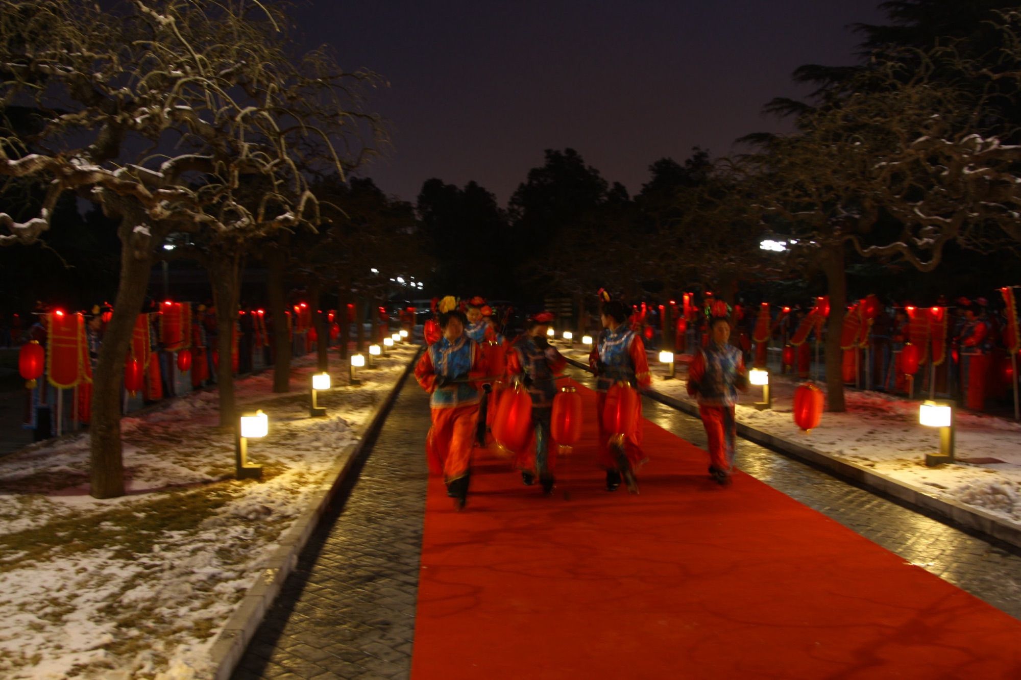 Greeters in palace dress lining the lantern-lit path into the Forbidden City