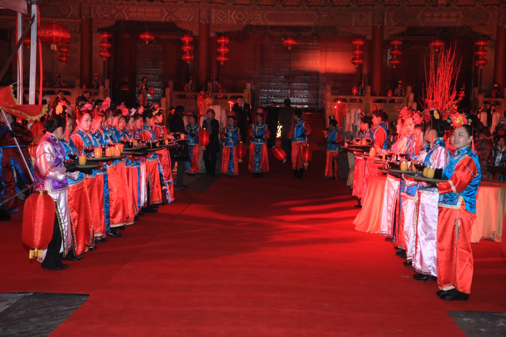 Greeters in traditional palace costume holding red lanterns along the red carpet