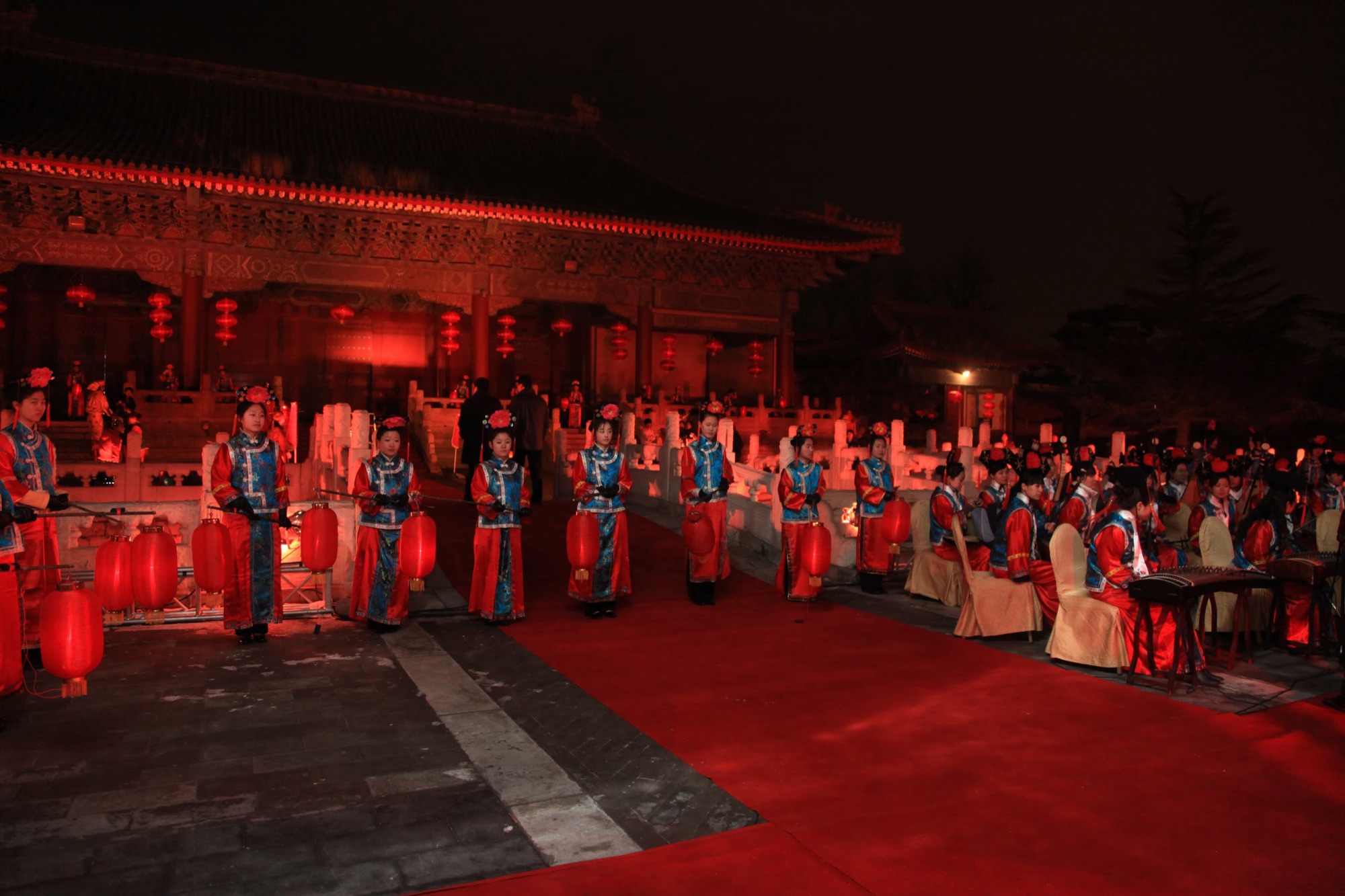 Guests arriving in the courtyard between rows of lantern-bearing greeters