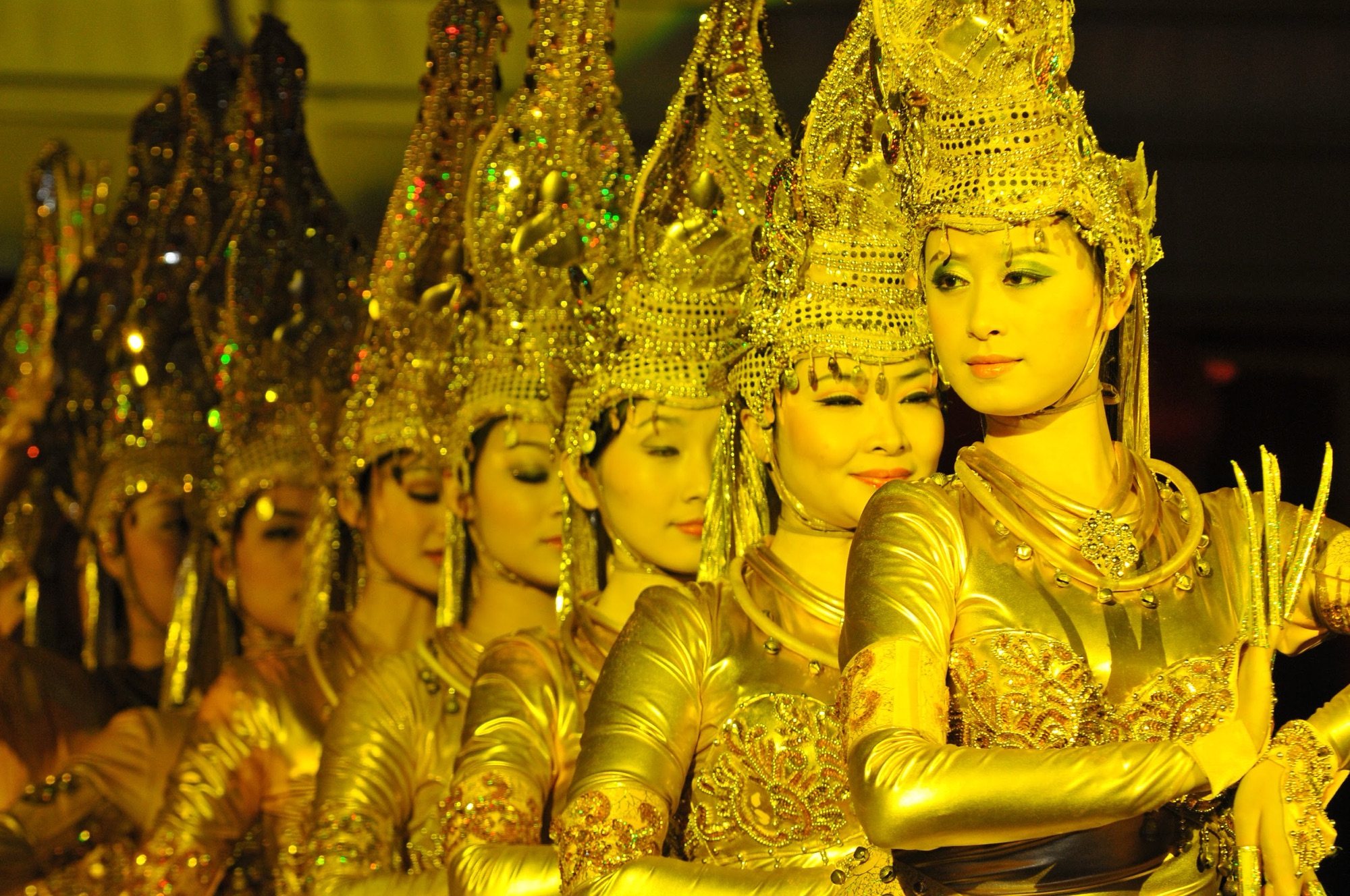 Performers in gold costumes and headdresses from the Thousand Hands show