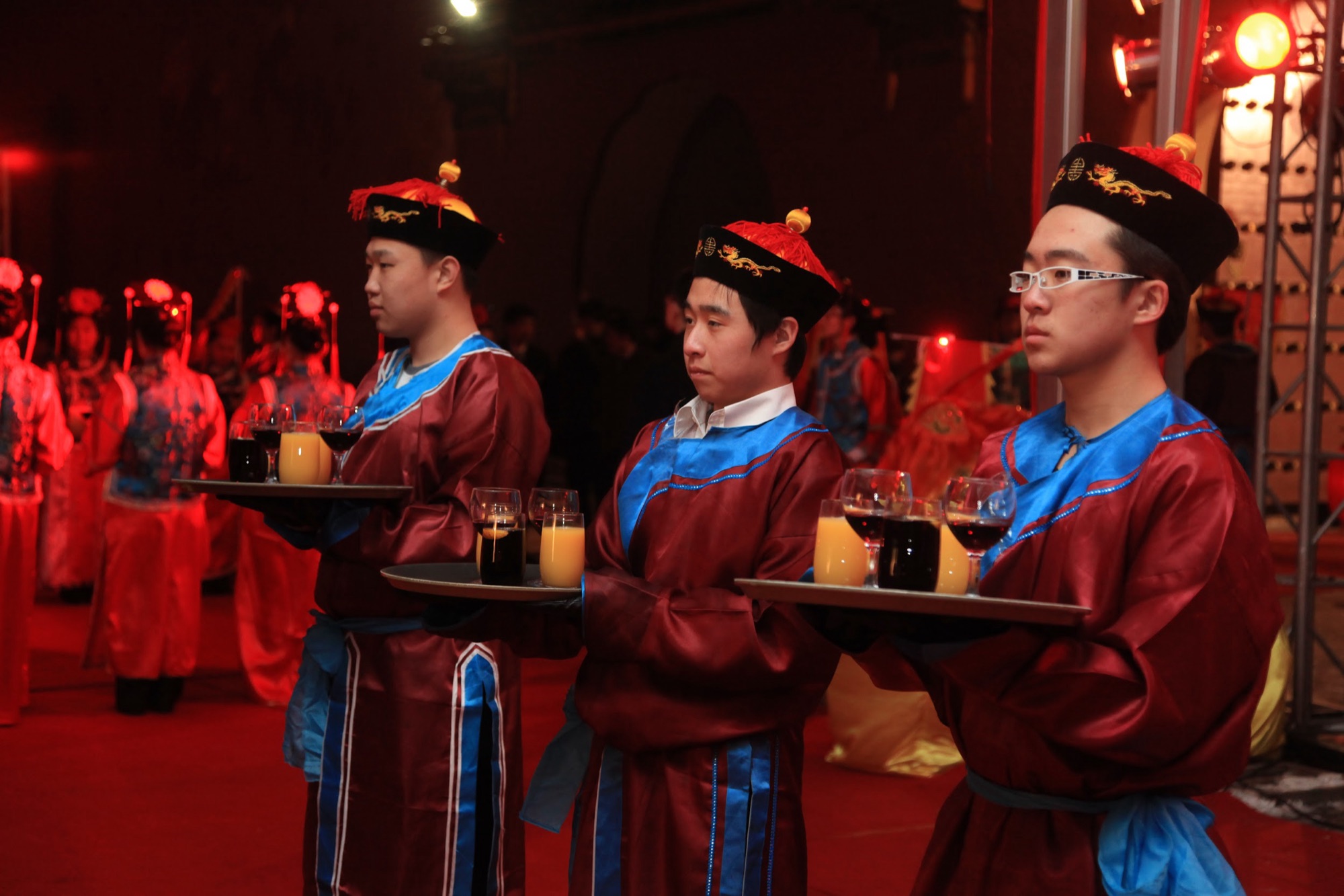 Servers in traditional costume carrying trays of drinks
