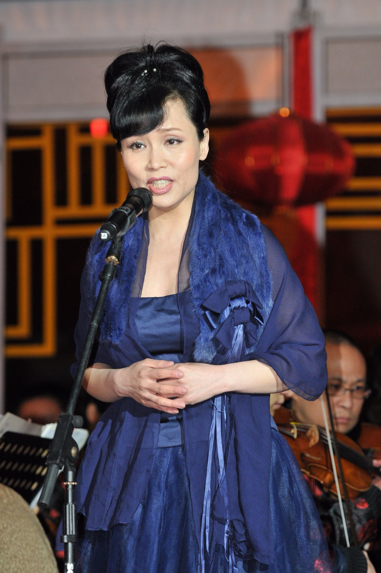 A singer in a blue gown performing with the orchestra