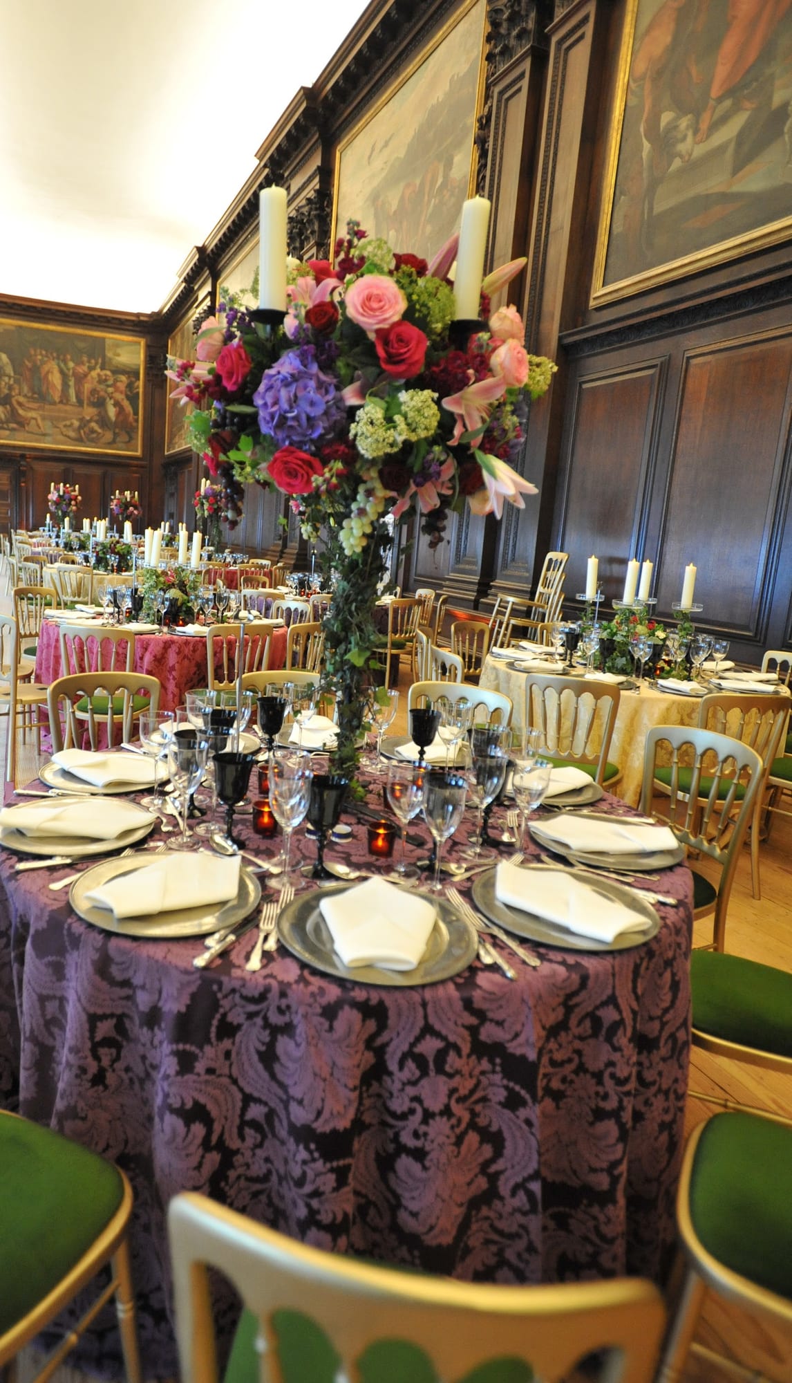 A dinner table with a tall floral centerpiece