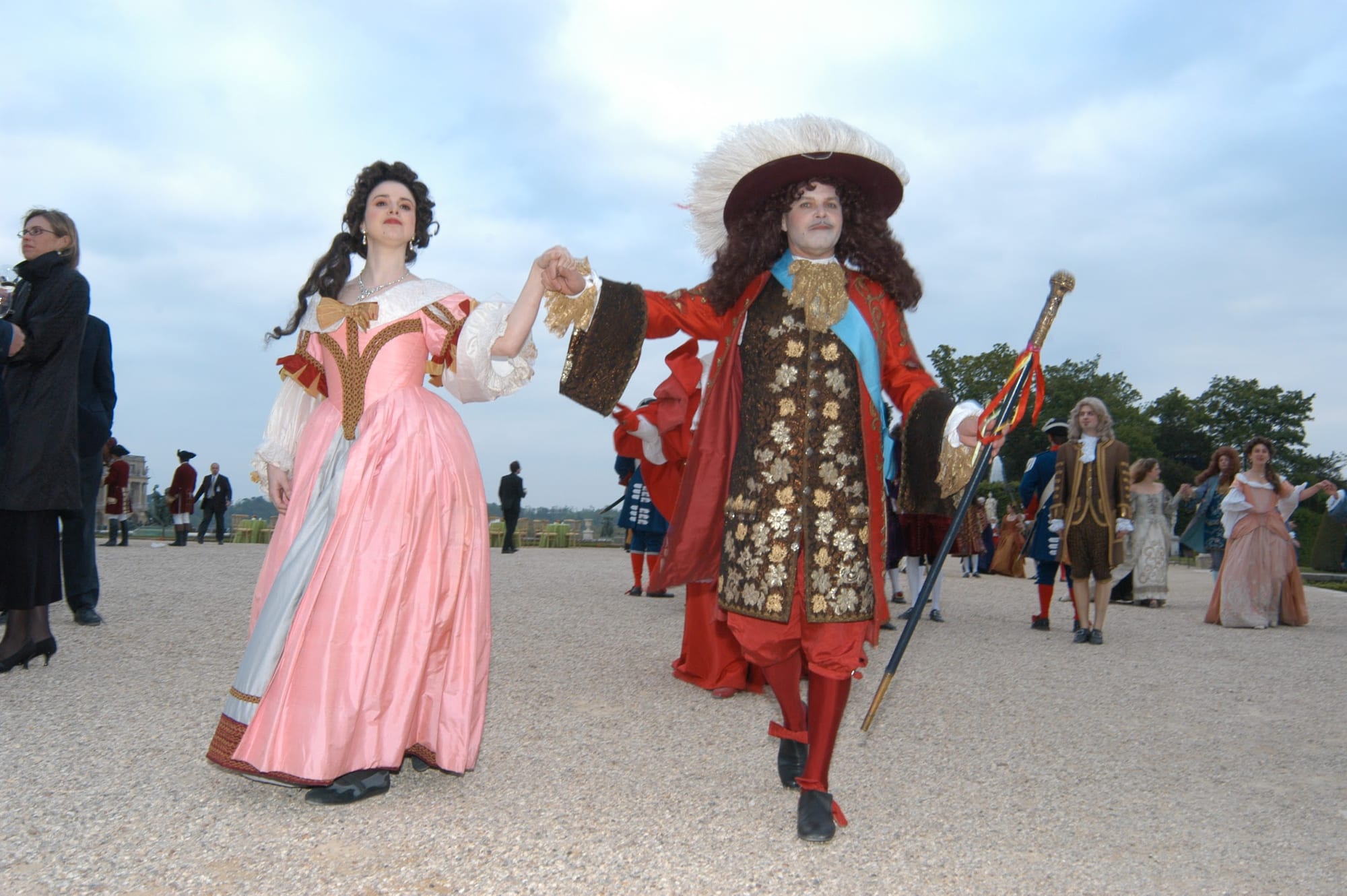 Performers in the court dress of Louis XIV arriving through the gardens