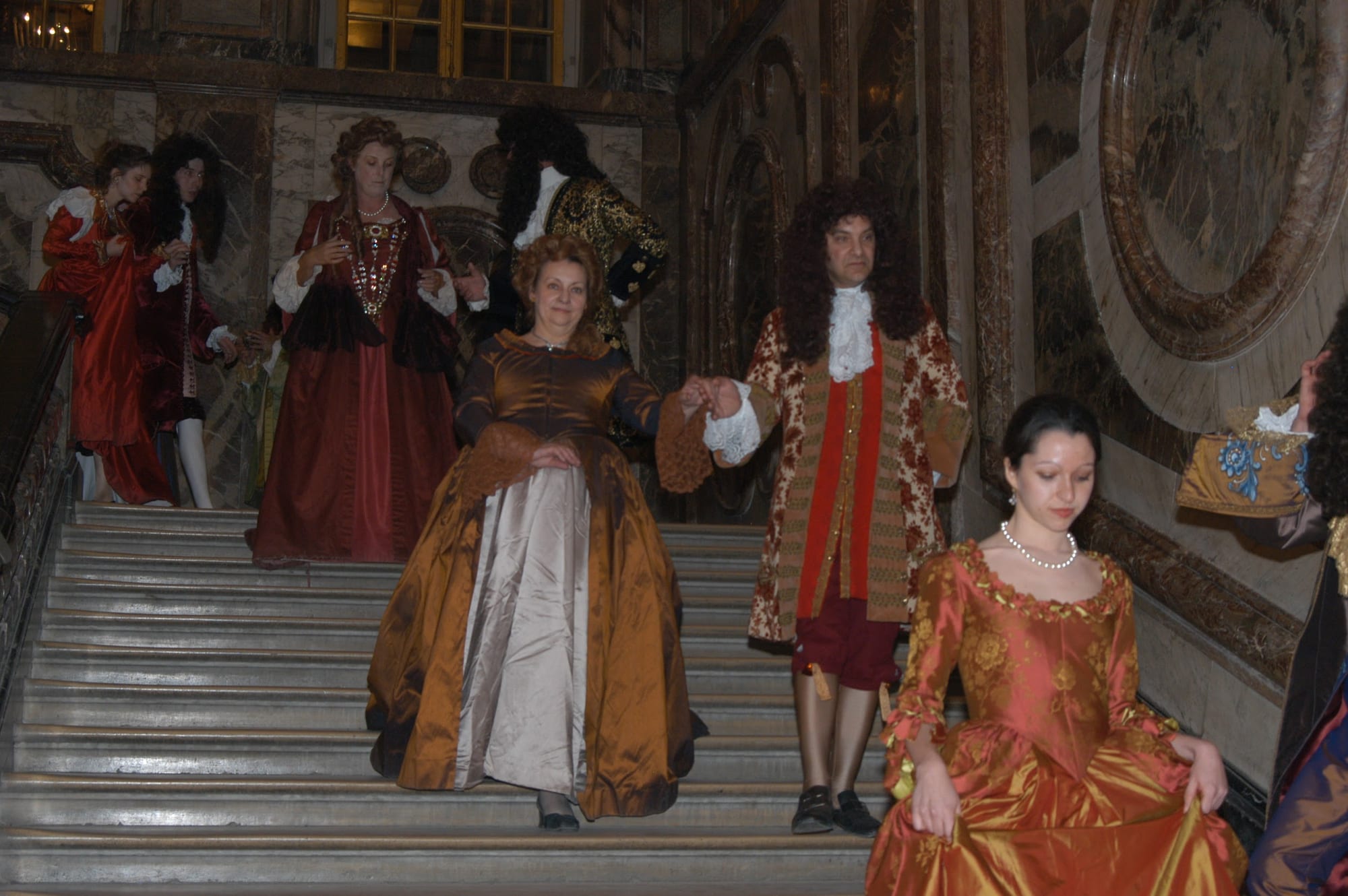 Performers in period dress descending a palace staircase
